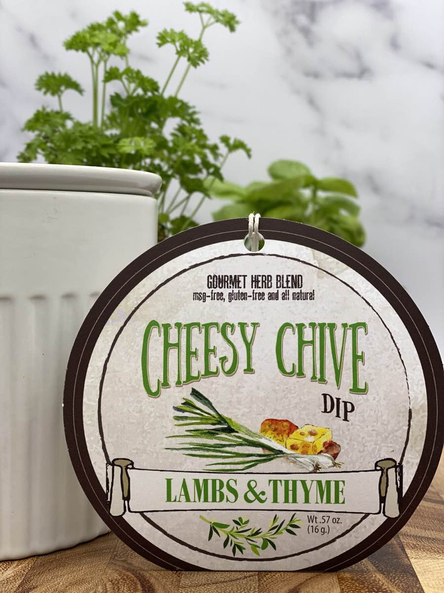 Cheesy Chive Dip product package displayed with dip chiller on wooden cutting board